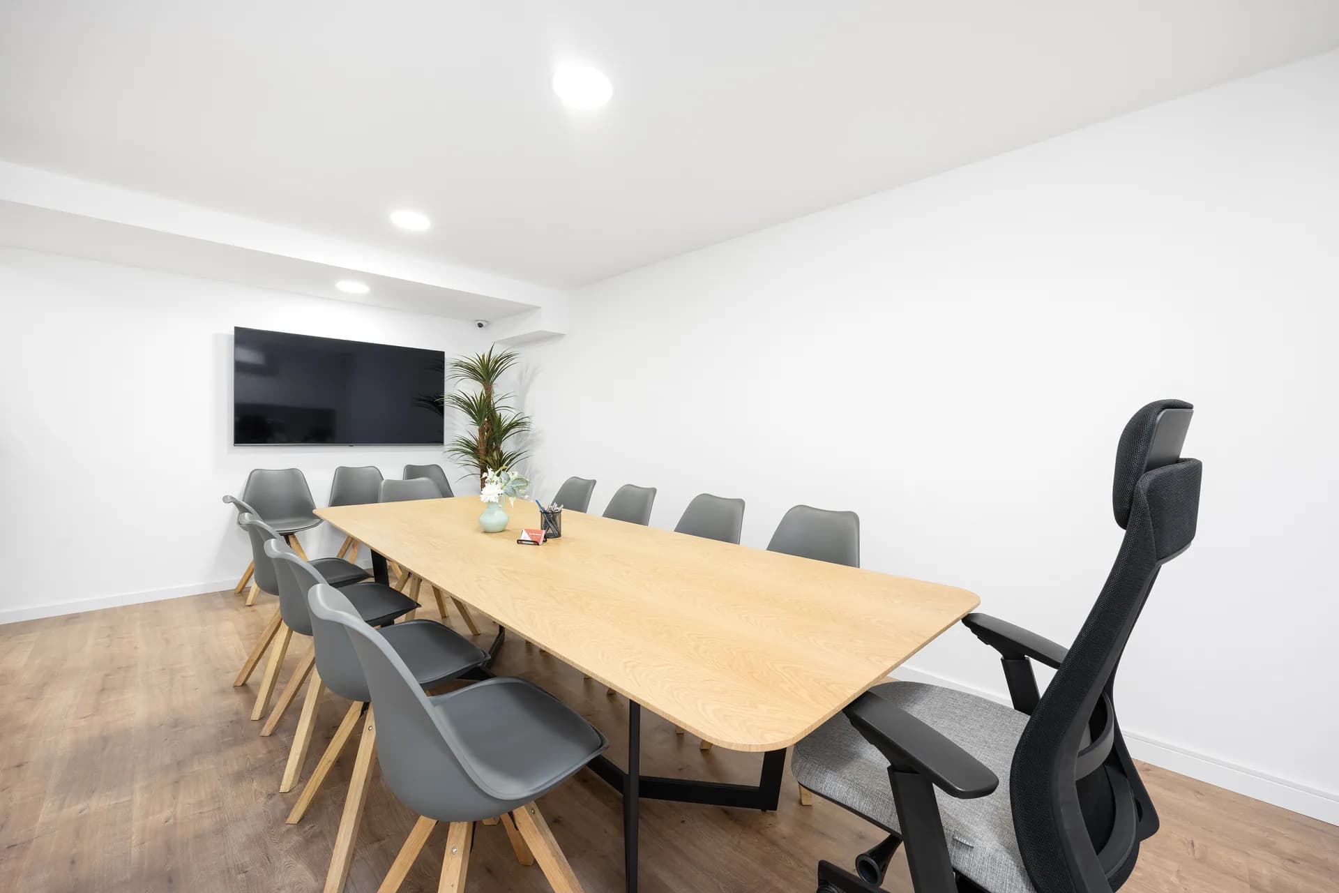 Sala de reuniões com mesa de carvalho e ecrã de televisão